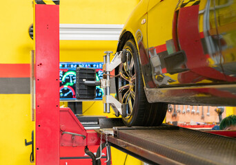 Car mechanic installing sensor during wheel alignment adjustment.