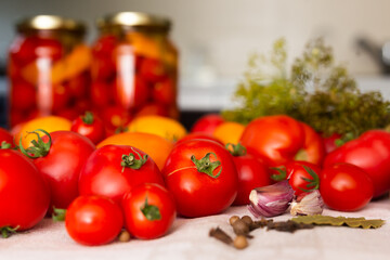 fresh red tomatoes, spices, seasonings and pickled tomatoes in jars on the table