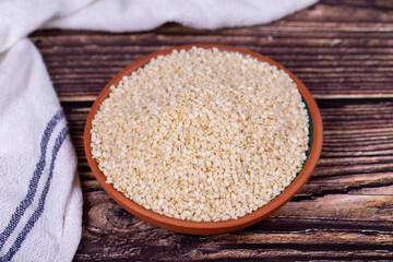 Sesame seeds on wooden background. Organic White Sesame seeds (Sesamum indicum) in Earthen bowl