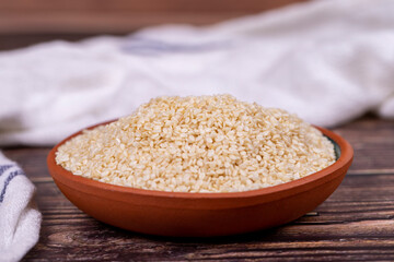 Sesame seeds on wooden background. Organic White Sesame seeds (Sesamum indicum) in Earthen bowl. Close up