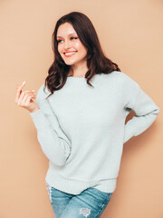 Young beautiful smiling female in trendy summer jeans and sweater clothes. Sexy carefree woman posing near beige wall in studio. Positive model isolated. Cheerful and happy