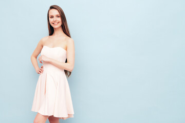 Portrait of young winsome woman in romantic attire pretty smiling on blue background. Slim female in pure pink dress posing in studio. Cheerful model. Isolated. Long hair