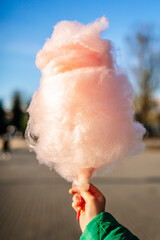 Cotton candy in the hand of a child in a summer park. Sweet food and sugar.