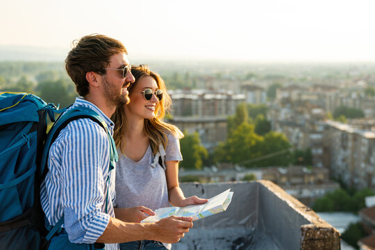 Happy couple on vacation sightseeing city with map. People travel fun love concept.