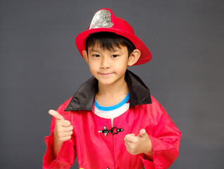 A young boy wearing a fireman hat and a red shirt.