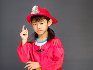 A young boy wearing a fireman hat and a red shirt.