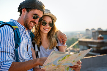 Happy tourists couple, friends sightseeing city with map together. Travel people concept.