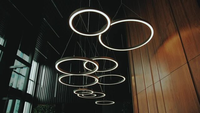 Modern chandelier in the lobby hangs from the ceiling. Hall of a hotel or restaurant, chandelier turned on slow motion dolly shot.