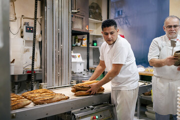 Baker picking bread from the conveyor belt