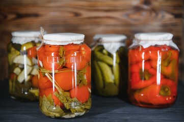 Jars of pickled vegetables on rustic wooden background