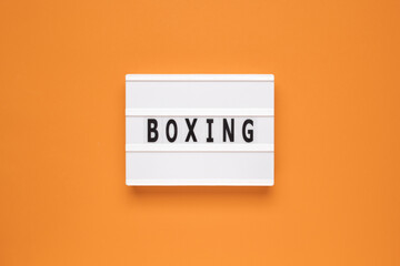The word boxing on lightbox isolated orange background.