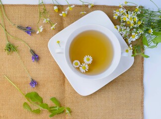 テーブルに載せたハーブティとフレッシュなハーブ、カモミールとミントとラベンダー