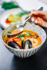 woman eating thai tom yum soup in a restaurant