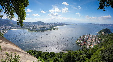 Landscape of Rio de Janeiro. Beautiful panoramic photo with this city from Brazil and its landmarks during a sunny day with blue sky and white clouds. View from Sugar Loaf mountain.