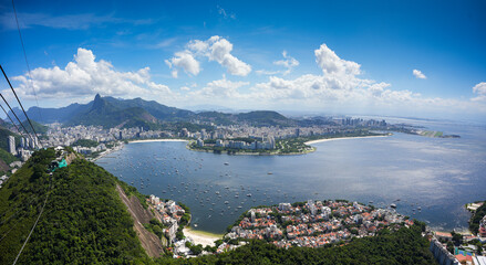 Rio de Janeiro from above. Beautiful landscape from Sugar Loaf mountain with the city of Rio de Janeiro and its landmarks during a sunny day with blue sky and white clouds. Travel to Brazil.