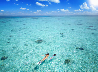 Aerial drone view of a mother and her daughter snorkeling in the turquoise, clear waters of the...