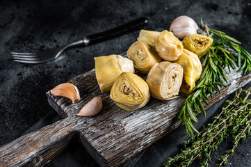 Artichokes hearts marinated with olive oil and herbs, pickled artichoke with garlic on wooden...