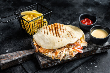 Turkish doner kebab in grilled pita bread with chicken meat. Black background. Top view