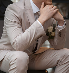 The groom is sitting in a beige suit.