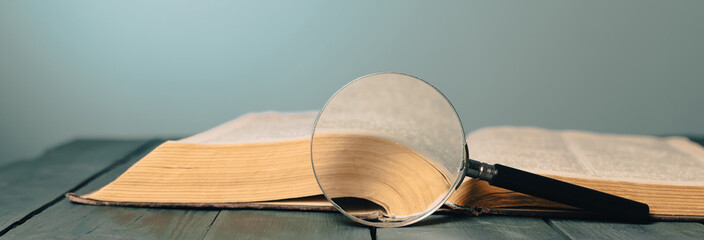 Book and magnifier on wooden table
