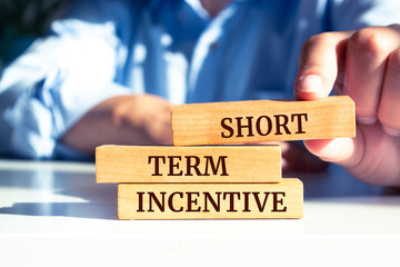 Close up on businessman holding a wooden block with "Short Term Incentive" message