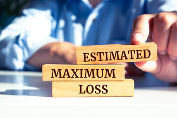Close up on businessman holding a wooden block with "ESTIMATED MAXIMUM LOSS" message