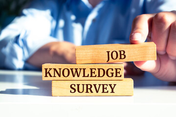 Close up on businessman holding a wooden block with "Job Knowledge Survey" message