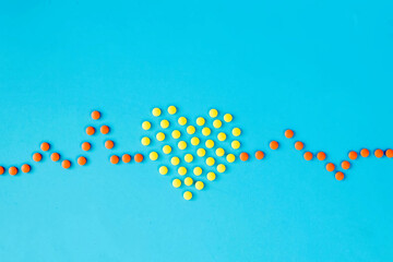 Medical pills in the shape of a heart and cardiogram, capsules on a blue background. Heart diseases