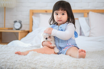 Fototapeta premium Little girl face lights up with a radiant smile as she holding her furry companions with love caressing their fur with endearment of warmth and care.