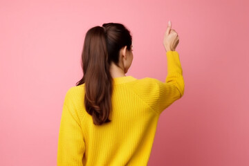 Back rear view of young brunette woman girl in yellow sweater posing isolated on pink wall background studio portrait, People sincere emotions lifestyle concept, Mock up copy space, Showing thumbs up