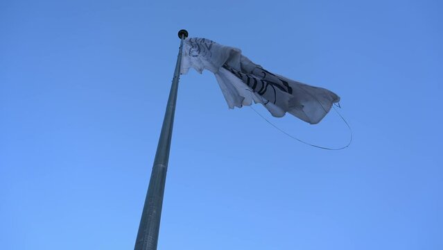 Ground view slomo of ragged Taliban Afghanistan flag and blue sky