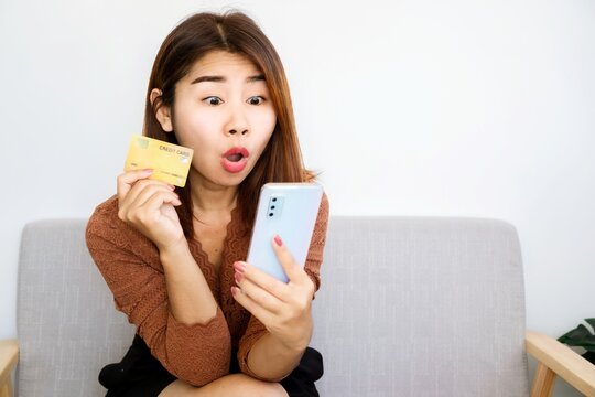 excited shopaholic Asian woman ready to pay for sale products hand holding credit card and mobile phone