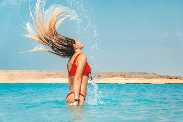 Naklejka premium Woman splashing water with her hair in ocean. Selective focus. Hair in motion blur.