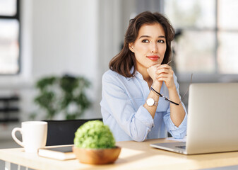 beautiful young smiling woman working remotely behind laptop at home.