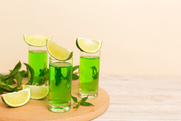 Sweet refreshing mint liqueur, with ice and mint leaves on table background, Shots with lime slice and mint flat lay