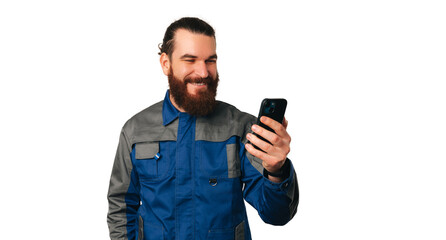 Handsome smiling young handyman in uniform has got a new client over the phone he is holding.