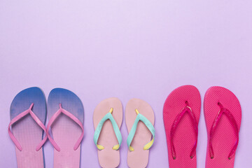 Many colorful flip flops on color background, top view