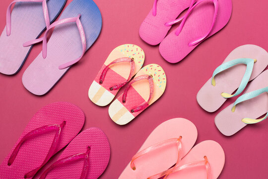 Many colorful flip flops on color background, top view