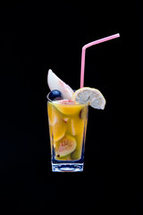 Pieces of tropical fruits in a glass with a plastic straw