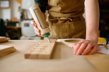 Closeup carpenter applying glue to board wooden timbers - obrazy, fototapety, plakaty