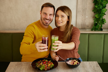 Mid adult couple enjoy eating salads and drinking smoothies in salad bar