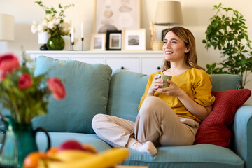 An attractive young woman relaxing at home drinking coffee
