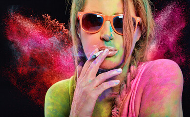 Beautiful woman covered in rainbow colored powder smoking a cigarette
