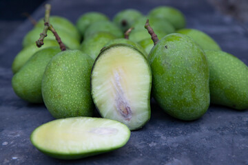 Closeup focus Fresh Raw  Mango with sliced mango on the concrete floor. Pickle ingredient