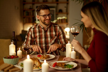 Beautiful couple having romantic dinner with candles and red wine at home