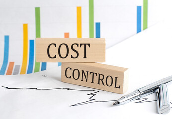 COST CONTROL text on notebook with pen and pencil on grey background