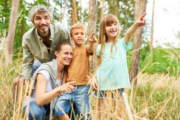 Happy family with two children hiking in nature and making discovery