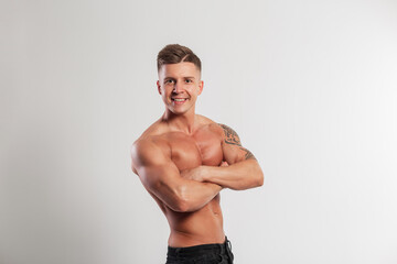 Fototapeta premium Handsome strong sports fit male instructor with a smile and a hairstyle with a muscular torso stands hand in hand on a white background