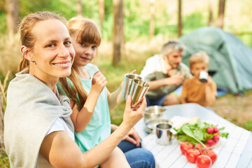Woman toasting mug with daughter during camp trip
