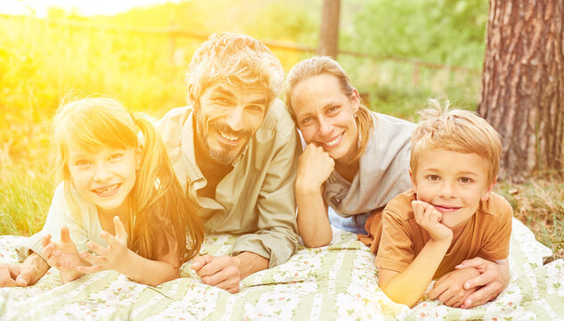 Smiling family with two children lying in park in nature
